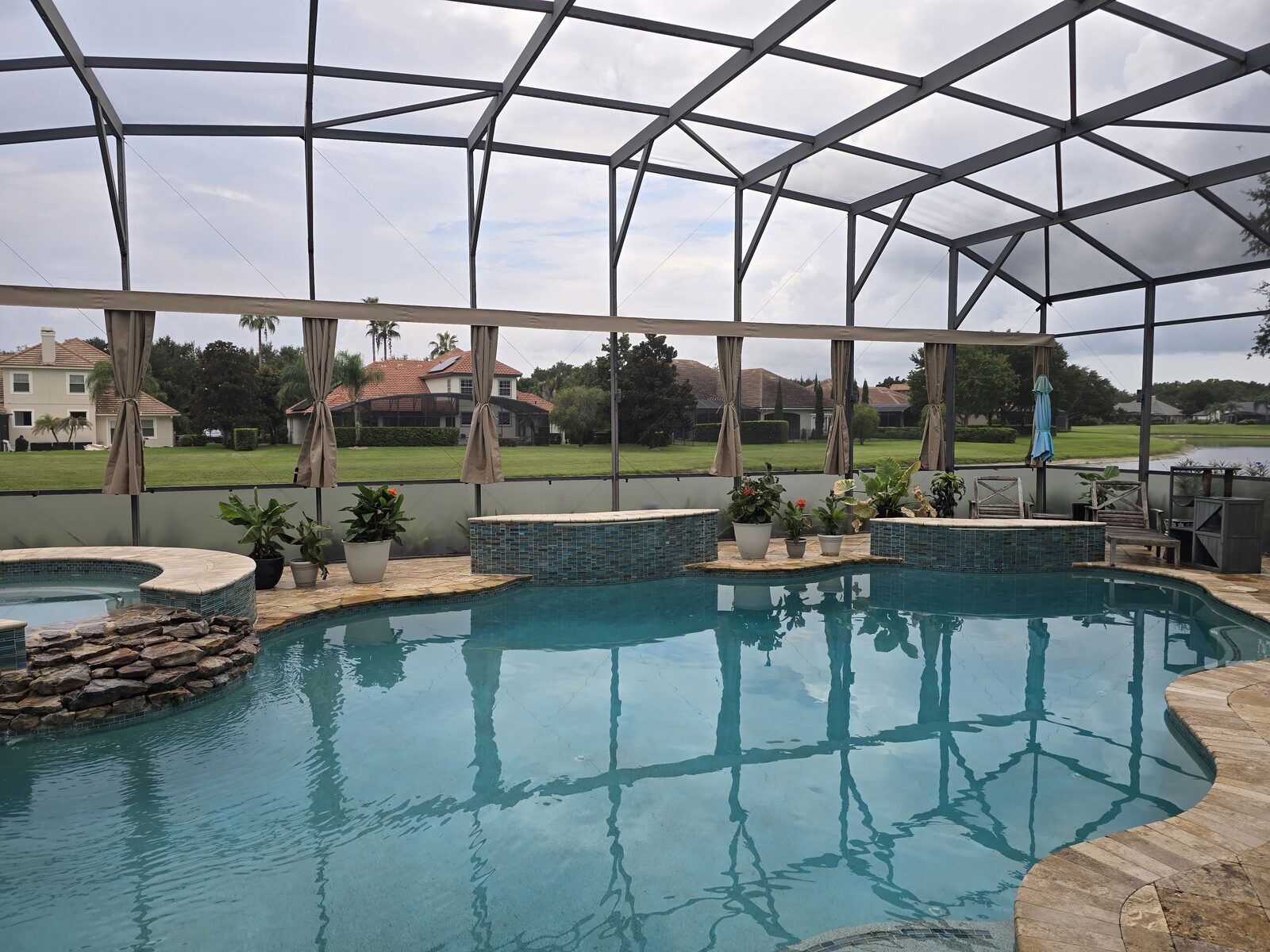 Outdoor privacy curtains around a screened pool and spa